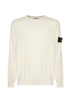 Suéter de manga larga color crema con cuello redondo, puños y dobladillo acanalados, con un parche del logo de Stone Island en negro y amarillo en la manga izquierda.