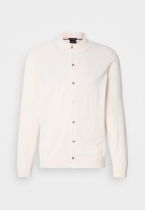 Ljus krämfärgad cardigan gjord av mjukt tyg, med krage, långa ärmar och en knappknäppning framtill med kontrasterande grå knappar.