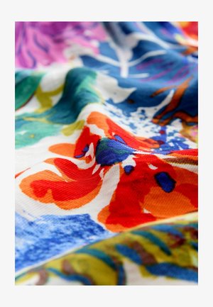 Tessuto floreale dai colori vivaci con motivi di fiori astratti in rosso, blu, verde e arancione, con trama e pieghe visibili.