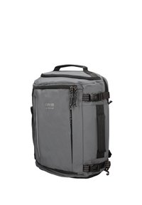 Sac à dos rectangulaire gris avec poche zippée à l'avant, sangles de compression latérales, poignée supérieure et logo "COVERI active" sur le panneau avant.