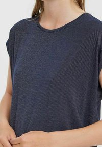 Námořnická modrá tričko s krátkým rukávem a kulatým výstřihem, s jemným pruhovaným vzorem a měkkou, hladkou texturou. Volný střih.