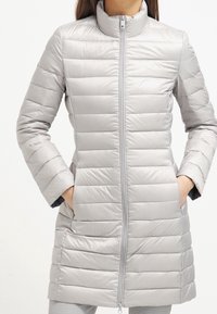 Jasnoszara, pikowana kurtka puchowa z wysokim kołnierzem, przednim zamkiem błyskawicznym i dwiema bocznymi kieszeniami; gładka tekstura, długość do kolan.