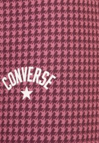 Roza tkanina s houndstooth vzorom v temnejših odtenkih, z belim napisom "CONVERSE" in z zvezdastim elementom na dnu.