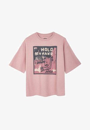 Różowa koszulka z krótkim rękawem ma centralny graficzny wzór z tekstem "TRZYMAJ MOJĄ RĘKĘ KIEDY RYSUJĘ" oraz abstrakcyjny wzór twarzy w kontrastowych kolorach.