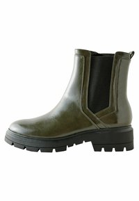 Botas de tobillo verde oliva hechas de material sintético brillante, con un panel elástico lateral y una suela de goma negra gruesa con textura.