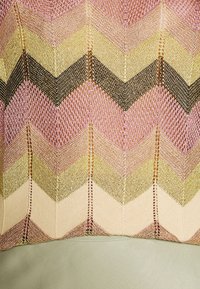 Knit textile featuring a chevron pattern in pink, gold, and black, with a soft green leather base. Textured and layered design.