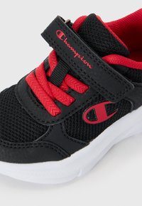 Svart og rød Champion-sneaker med røde lisser, borrelås, mesh-overdel og hvit såle, skrått bilde på hvit bakgrunn.