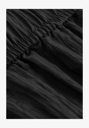 Must tänavainete kokku tõmmatav elastne detail, mis demonstreerib pehmet, kortsulist tekstuuri ja voolavat langust. Sobib erinevatele rõivastele.