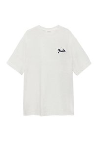 Valkoinen puuvillainen t-paita, jossa on rento istuvuus, pyöreä kaula-aukko ja lyhyet hihat; vasemmassa rinnassa musta "Fender"-logo.