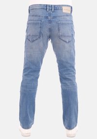 Světlé modré džínové kalhoty s úzkým střihem, s nášivkou na pásku, dvěma zadními kapsami s trojúhelníkovými klopami a jemným vyblednutím.