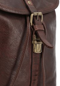 Bruine leren tas met een messing gesp en sluiting die een riem op de voorflap beveiligt.