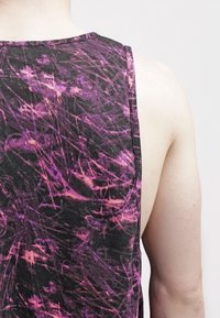 Černý top na ramínka s živým abstraktním vzorem v purpurové a růžové barvě. Materiál vypadá měkce, má volný střih a neobsahuje žádné ozdoby.