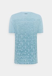 Vaaleansininen lyhythihainen urheilupaita, jossa on tekstuurilla varustettu "Under Armour" -tekstimalli ja logo yläselän kauluksessa.