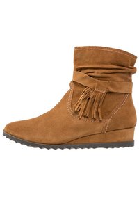 Bruine suède enkellaars met een slouchy ontwerp, franjerdetails en een wigvormige hak. Voorzien van een gestructureerde rubberen zool en contrasterend stikwerk.