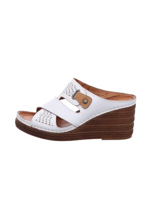 White wedge sandals with perforated upper, two straps, a brown decorative buckle, and a textured brown platform sole.
