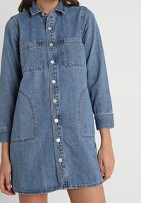 Denimskjortklänning i ljusblått med långa ärmar, knäppning fram, två bröstfickor och sidfickor. Har en avslappnad passform och rak nederkant.