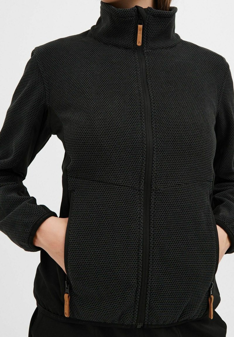 Czarna kurtka zapinana na zamek z teksturowanej tkaniny, z wysokim kołnierzem i dwiema bocznymi kieszeniami; wyposażona w drewniane uchwyty do zamka.