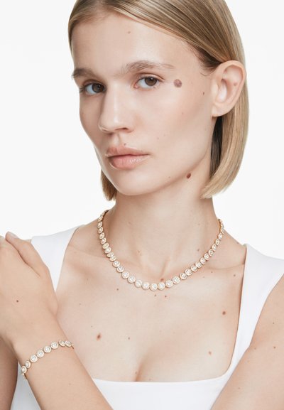 Collier et bracelet en ton or avec des montures circulaires ornées de pierres précieuses claires et étincelantes. Fini lisse et poli avec un design classique.