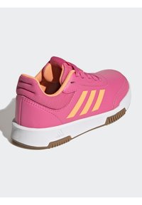 Scarpa sportiva rosa con tre strisce gialle, tomaia texturizzata, collare imbottito e suola intermedia bianca. Presenta una suola in gomma per una migliore aderenza.