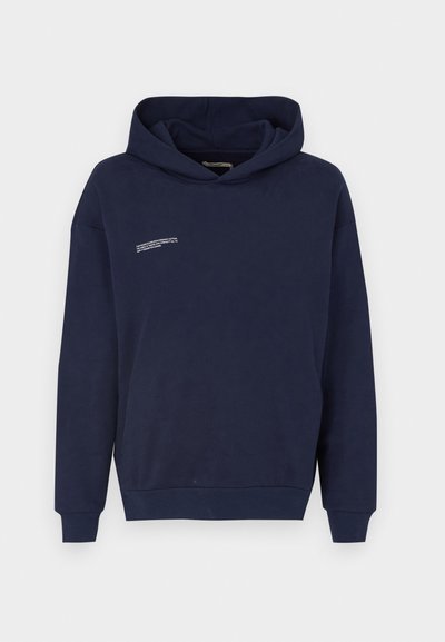 Tumši zila kapuce ar priekšējo kangaroo kabatu, garām piedurknēm un regulējamu kapuci. Ar baltu tekstu augšējā kreisajā stūrī. Mīksts materiāls.