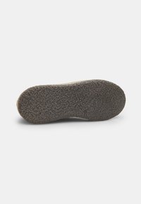 Rubberen schoenzool met een gestructureerd, gripachtig oppervlak in donkergrijs, dat naar de rand toe taps toeloopt met een lichte kromming.