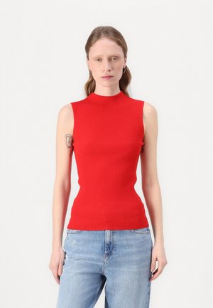 Red ribbed sleeveless top with a high neckline. Fitted shape with a textured fabric. Worn with light blue relaxed-fit jeans.