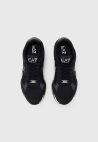 Μαύρα αθλητικά παπούτσια με επάνω μέρος από δίχτυ, γκρι λεπτομέρειες, παχύ λευκό πέλμα και λογότυπο στη γλώσσα. Διαθέτουν κορδόνια και ενισχυμένο μύτη.