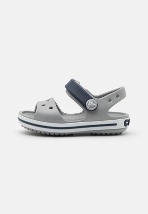 Gray rubber sandals with navy strap, perforated upper, adjustable hook-and-loop closure, textured outsole, and white stripe detail.