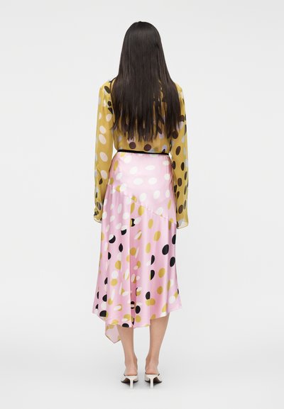 Žltá blúzka s dlhými rukávmi a viacfarebnými bodkami, v kombinácii s ružovou asymetrickou sukňou so podobným vzorom. Hladká látka.