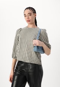 Camicia a quadri bianca e nera con maniche a sbuffo, abbinata a pantaloni in pelle nera e una borsa azzurro chiaro. Design minimalista, texture liscia.