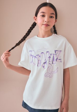 Junges Mädchen mit langem geflochtenem Haar hält einen Zopf, trägt ein weißes T-Shirt mit lila "Bratz" Text und Schmetterlingsgrafik.