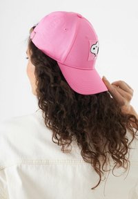 Rosa Baseballkappe aus Baumwolle, mit einem Aufnäher eines weißen Comic-Charakters. Verstellbarer Riemen hinten, mit einem leicht gebogenen Schirm.