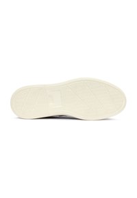 Suela de zapatilla, de goma blanca con patrones de agarre texturizados, forma ligeramente curvada, que presenta un parche con el logo central sobre una base sólida.