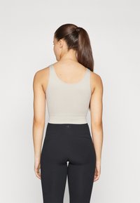 Sports-bh i lys grå ribbet stoff med scoop-rygg, kombinert med høyt liv svarte leggings. Enkel design, tettsittende form.