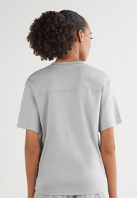 Jasnoszary t-shirt z krótkim rękawem o luźnym kroju. Posiada okrągły dekolt, miękką teksturę oraz prosty szew z tyłu.