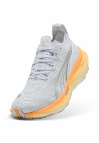Scarpa atletica bianca con una tomaia in mesh testurizzato, soletta arancione e dettagli grigi. Presenta una punta arrotondata e lacci per una vestibilità sicura.