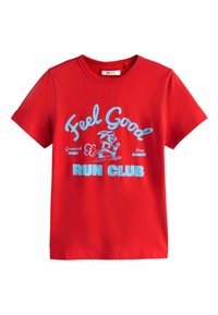 Sarkana kokvilnas T-krekls ar īsām piedurknēm un apaļu kaklu. Uz tā ir zilas grafiskas zīmes ar uzrakstu "Feel Good RUN CLUB" un skrienoša zaķa ilustrācija.