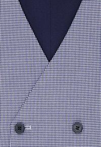 Kamizelka w wzór houndstooth w kolorze granatowym i białym z głębokim dekoltem w serek, z podwójnym zapięciem na guziki i teksturowanym materiałem. Posiada gładką podszewkę.