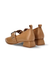 Zapatos de cuero marrón con punta cuadrada y tacón bajo tipo bloque. Presentan una correa ajustable con hebilla y detalles de perforación circular.