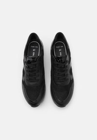 Baskets noires avec une tige en mesh texturé et des accents brillants, dotées d'un design à lacets et d'un branding discret sur les semelles intérieures. Taille 37.