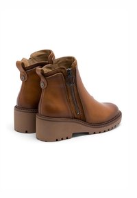 Botas de tobillo de cuero marrón con una cremallera lateral, punta redondeada y tacón grueso. Cuenta con una suela texturizada y forro de tela.