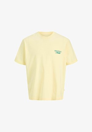 Halvány sárga rövid ujjú póló kerek nyakkivágással és zöld "ORIGINALS Studio" felirattal a bal mellrészen.