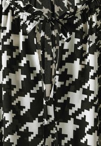 Sorte og hvide mønstrede stof med et abstrakt zigzag-design, med en samlet talje og blød tekstur.