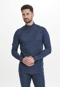 Mörkblå långärmad topp med kvartslång dragkedja i texturerat tyg, med en upphöjd krage, figurnära ärmar och diskreta stygnsdetaljer.