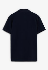 Polo de color azul marino, de manga corta, con cuello clásico, textura suave, color sólido, sin patrones ni logotipos visibles. Diseño limpio y minimalista.