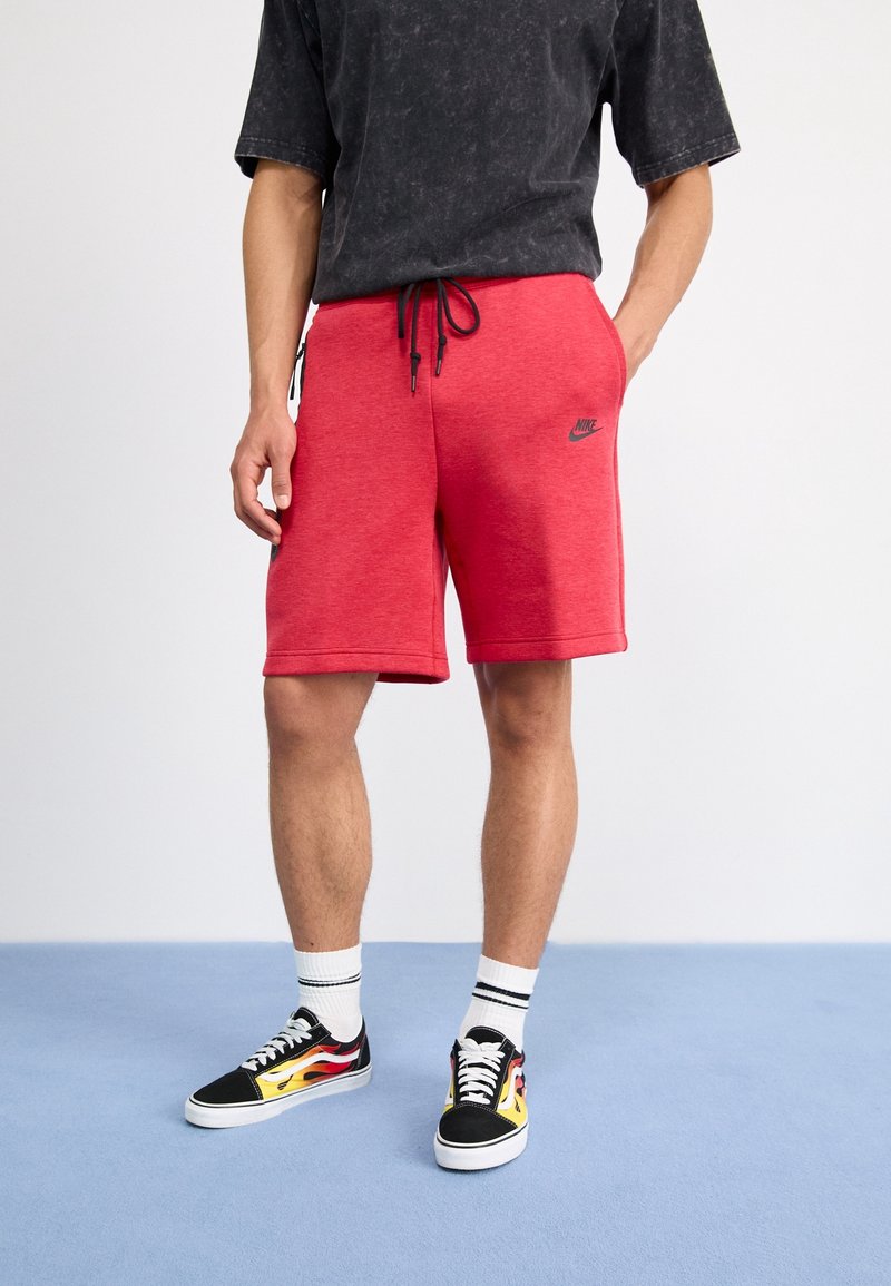 Červené šortky z bavlněné směsi s elastickým pasem a šňůrkou, se černým logem Nike. Spárované s černými teniskami s barevnými akcenty.