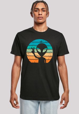 Black cotton T-shirt featuring a colorful alien graphic in a circular design with horizontal stripes in turquoise, orange, and yellow.