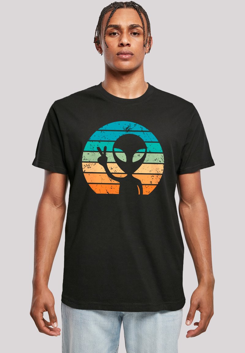 Schwarzes Baumwoll-T-Shirt mit einem bunten Alien-Design in einem kreisförmigen Muster und horizontalen Streifen in Türkis, Orange und Gelb.