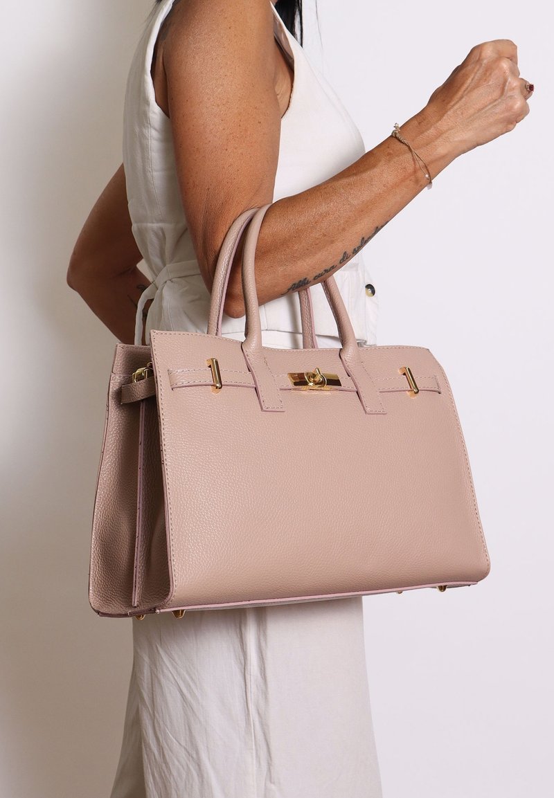 Borsa a tracolla in pelle rosa chiaro con design strutturato, manici superiori doppi e dettagli in metallo dorato. Superficie texturizzata con fondo piatto.