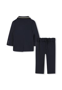Granatowy garnitur dla dzieci z marynarką z kolarskim kołnierzem w złotym kolorze oraz dopasowanymi spodniami z elastycznym pasem. Gładka textura.